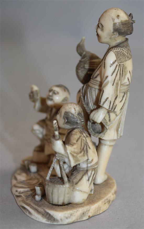 A Japanese carved ivory okimono group of street vendors, Meiji period,(-)